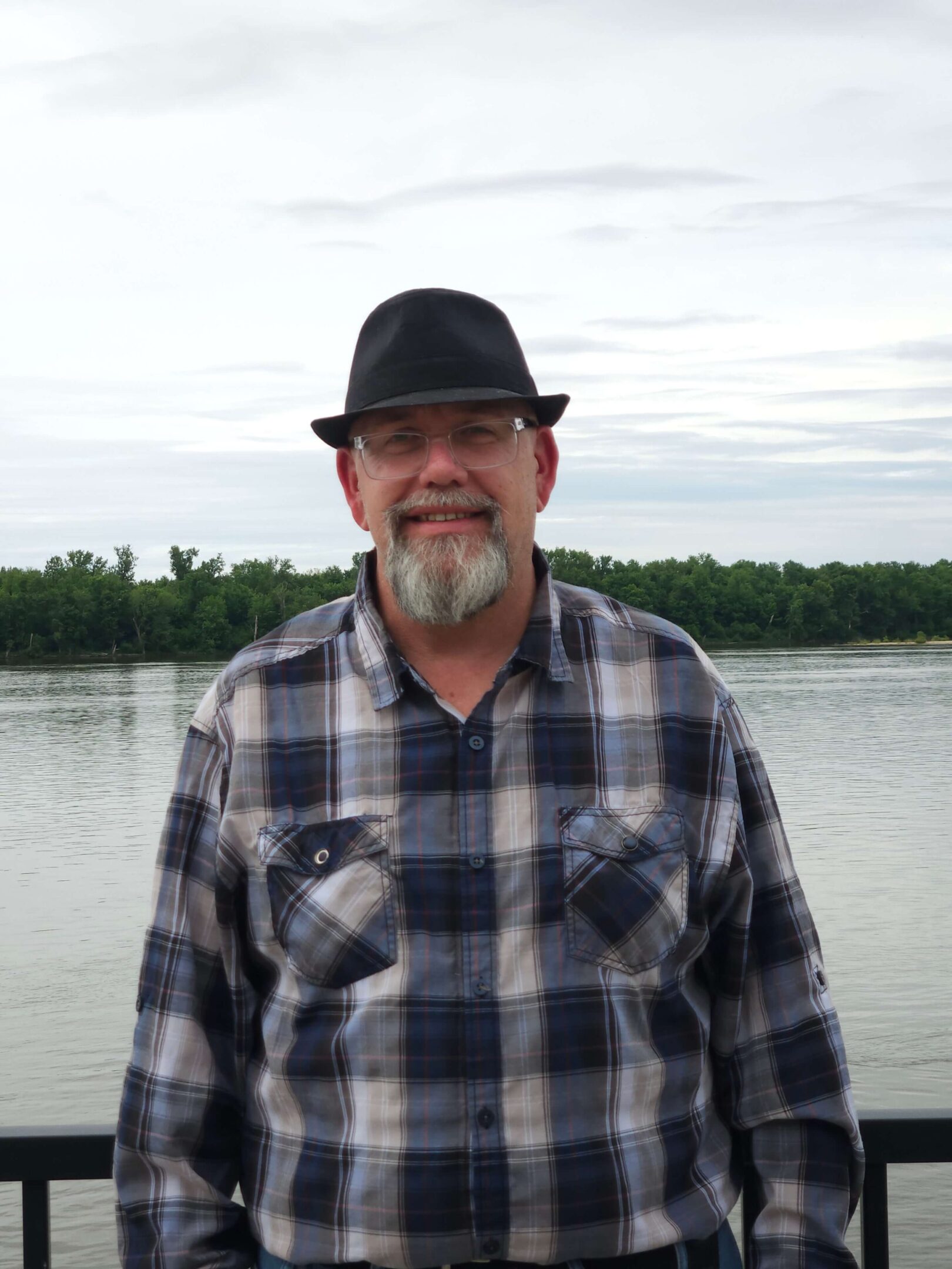 Man in hat by a lake.