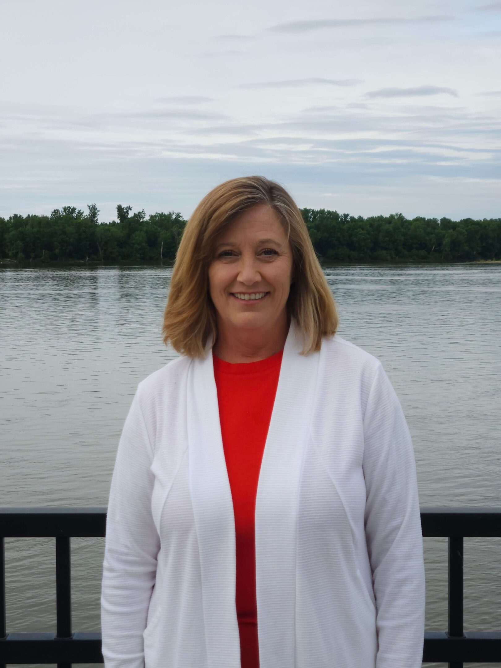 Woman standing by a lakeside railing.