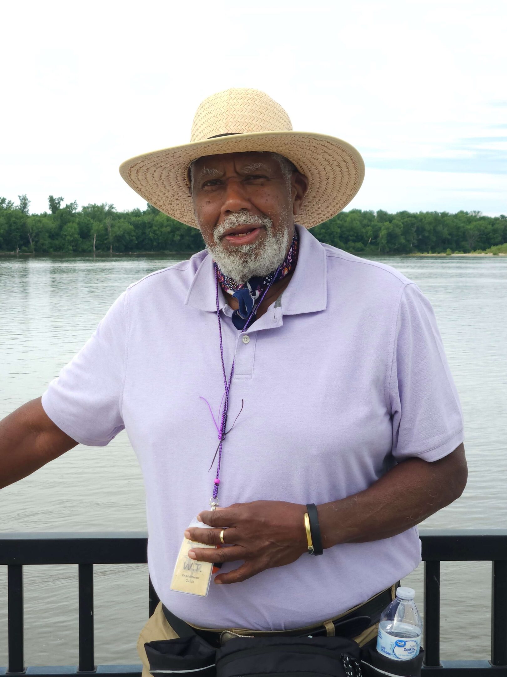 Man wearing straw hat by a river.
